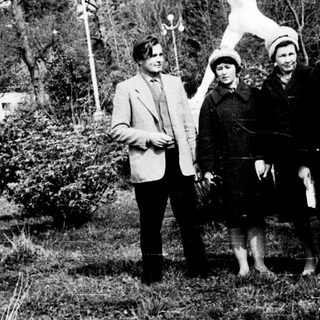 Four people posing outdoors near a statue.
