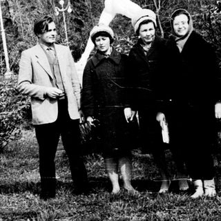 Four people posing outdoors near a statue.