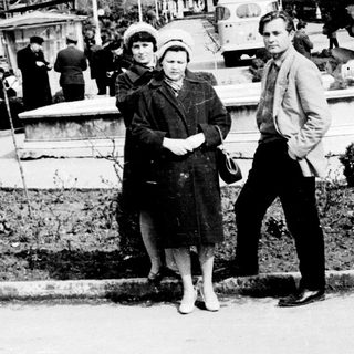 People posing near a fountain in a park.
