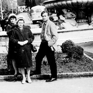 People posing near a fountain in a park.