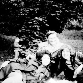Family posing happily outdoors on grass.