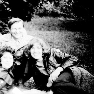 Family posing happily outdoors on grass.