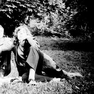 Three individuals posing together outdoors in a wooded area.