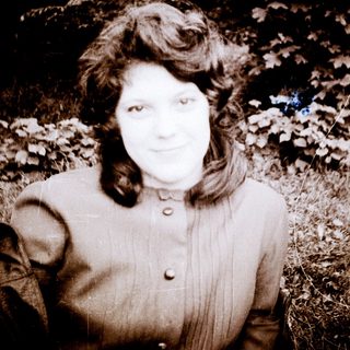 Woman posing outdoors in vintage-style black-and-white photo.