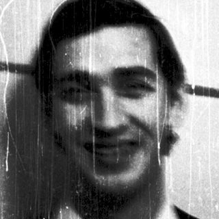 Man smiling in a shower with rain-like water.