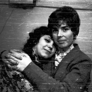 Two people hugging affectionately in a vintage-style photograph.
