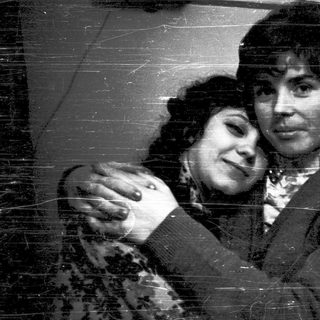 Two people hugging affectionately in a vintage-style photograph.