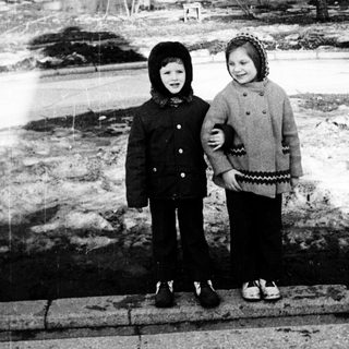 Two children standing on a snowy path in winter park.