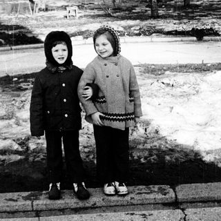 Two children standing on a snowy path in winter park.