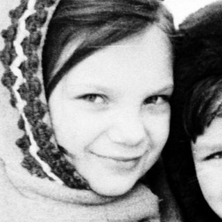 Two children smiling together in winter clothing.