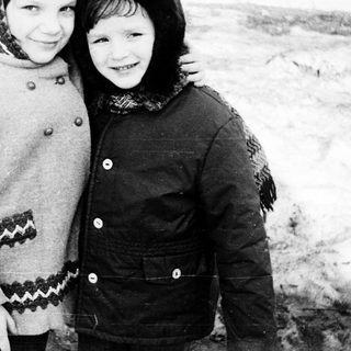 Two children smiling together in winter clothing.