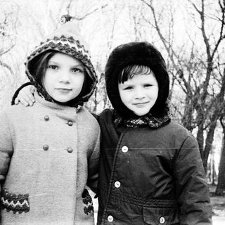 Two children posing outdoors in winter clothing.