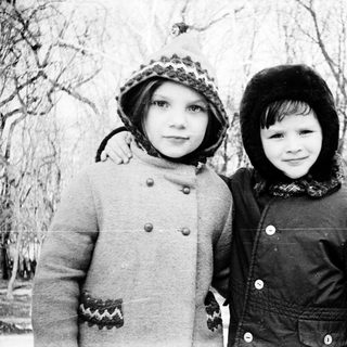 Two children posing outdoors in winter clothing.