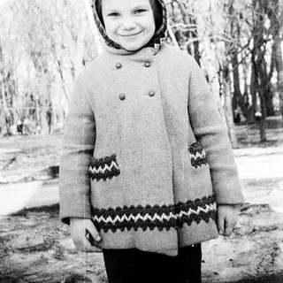 Young girl wearing winter coat and headscarf outdoors.
