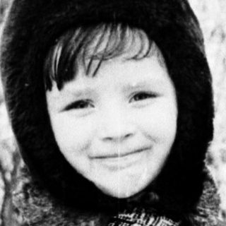 Child smiling outdoors in winter attire.