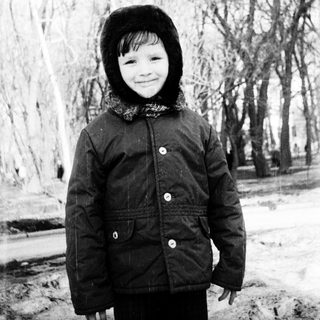 Child smiling outdoors in winter attire.