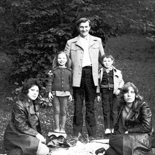 Family group photo outdoors near campfire.