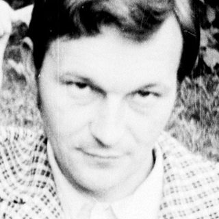 Man sitting outdoors holding a book.