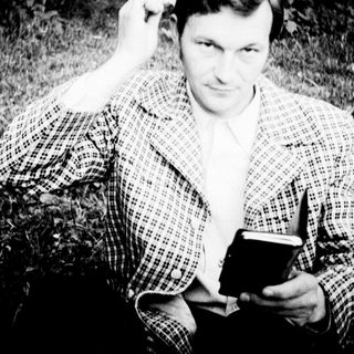 Man sitting outdoors holding a book.