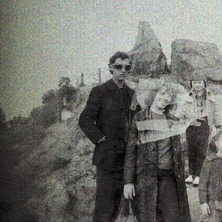 Family hiking with luggage on rocky terrain.