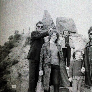 Family group posing outdoors near rocky terrain.