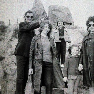 Family group posing outdoors near rocky terrain.