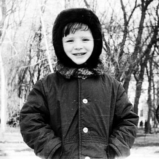 Child smiling outdoors in winter attire.