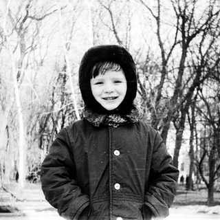 Child smiling outdoors in winter attire.