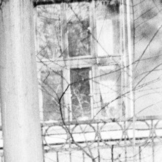 Child playing on swing in damaged, post-war urban area.