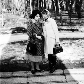 Two women posing closely outdoors in winter attire.