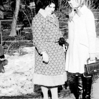 Two women conversing outdoors in winter attire.