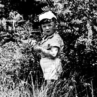 Child in military uniform near roadside.