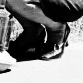 A woman kneeling outdoors holding a child.