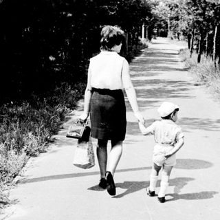 A woman and child walking hand-in-hand on a rural path.