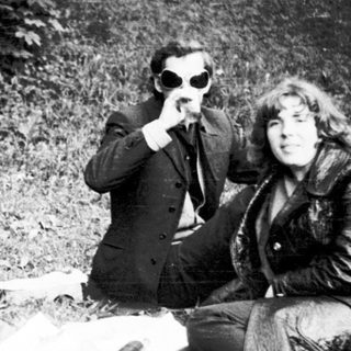 Three people sitting outdoors, posing playfully with sunglasses.