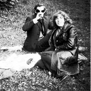 Three people sitting outdoors, posing playfully with sunglasses.