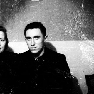 Two individuals in formal attire posing indoors.