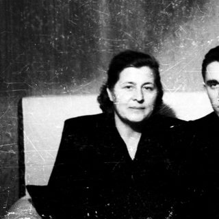 Two individuals in formal attire posing indoors.