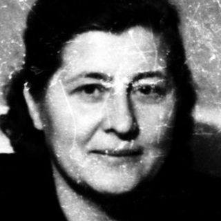 A woman in formal attire seated indoors.