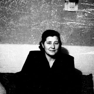 A woman in formal attire seated indoors.