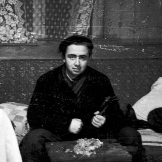 Young man playing traditional stringed instrument indoors.