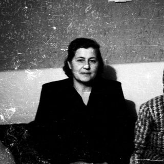 Two women seated indoors, dressed in mid-20th century clothing.