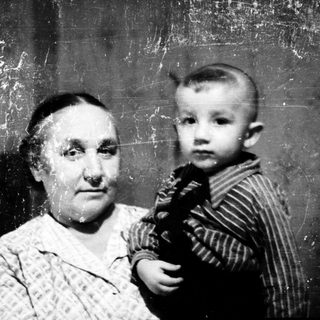 Old woman holding young child indoors.