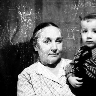 Old woman holding young child indoors.