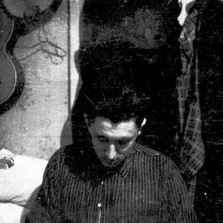 Vintage photo of person playing guitar indoors.