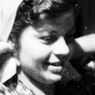 Vintage black-and-white portrait of smiling woman in headscarf.