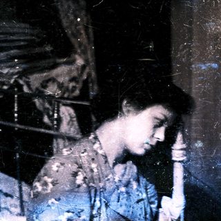 A person leaning on a pillar in dim lighting.