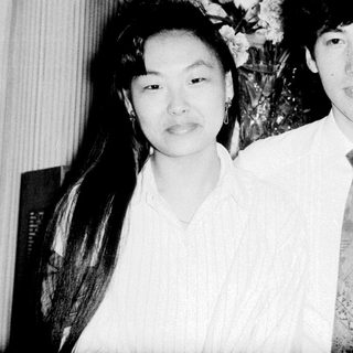 Two people posing formally indoors with floral arrangement.