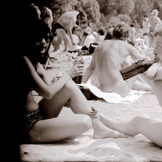 Nude beach scene with people relaxing outdoors.