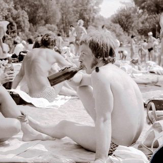 Nude beach scene with people relaxing outdoors.